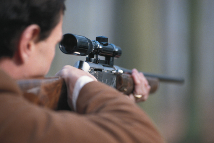 Man aiming rifle, close-up, rear view